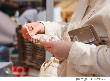 A Woman Counting Cash at Market with Wallet and Beige Purse 126293777