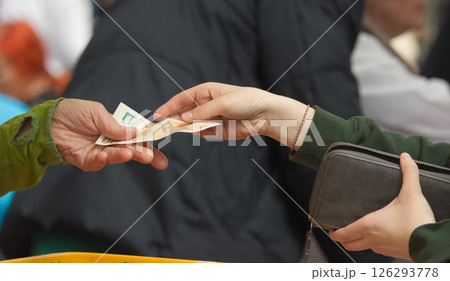 Two Hands Exchanging Cash in a Public Outdoor Market 126293778