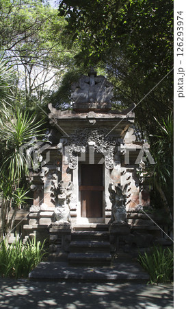 Traditional Balinese temple gate with intricate stone carvings and guardian statues surrounded by lush greenery and natural light in a serene outdoor setting in Bali 126293974