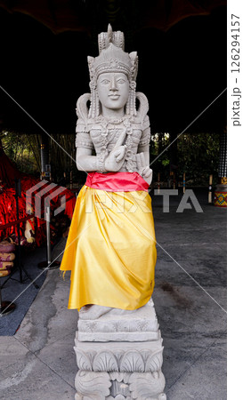 Sacred Balinese Hindu Stone Statue Draped in Yellow and Red Cloth in an Open Temple Setting 126294157