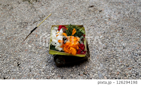 Beautifully Arranged Balinese Offering Basket with Colorful Flowers on Pebbled Ground for Traditional Hindu Rituals in Bali. 126294198