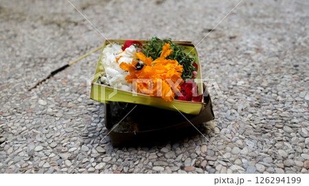 Beautifully Arranged Balinese Offering Basket with Colorful Flowers on Pebbled Ground for Traditional Hindu Rituals in Bali. Beautifully Arranged Balinese Offering Basket with Colorful Flowers on Pebbled Ground for Traditional Hindu Rituals in Bali. 126294199
