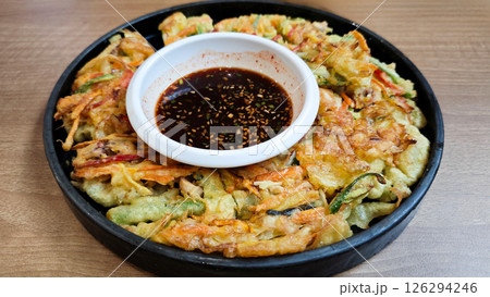 Close-up of Korean Haemul Pajeon Seafood Pancake with Soy Dipping Sauce on Black Plate on Wooden Table 126294246