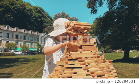 A smart little girl builds the big tower with toy wooden bricks A smart little girl builds the big tower with toy wooden bricks 126294331
