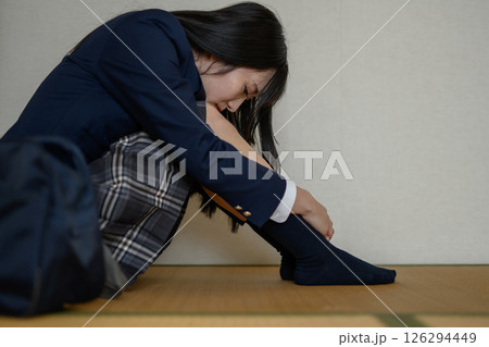 和室内で体育座りする女子高生　いじめ　不登校　ひきこもり　将来の不安　ナチュラルカラー 126294449