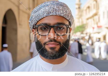 Young middle eastern adult male wearing glasses and traditional headwear outdoors. 126295214