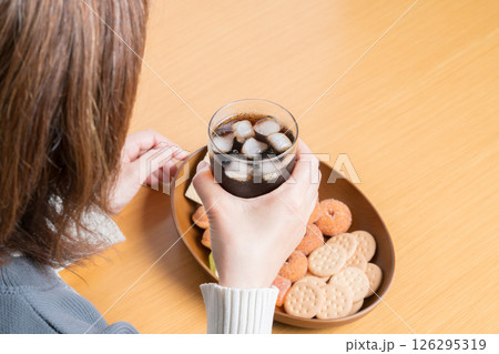 おやつにお菓子の盛り合わせを食べながらコーラを飲む女性 126295319