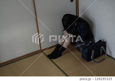 和室内の隅で体育座りする女子高生　いじめ　不登校　ひきこもり　将来の不安　 126295325