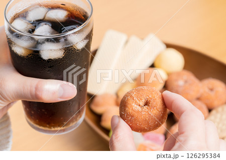 コーラを飲みながらお菓子の盛り合わせを食べる女性の手元 126295384