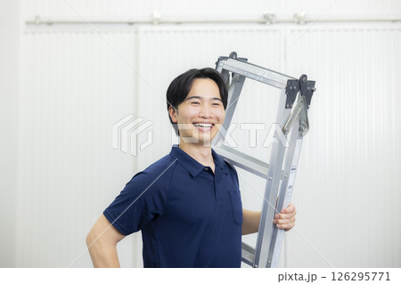 脚立を持ってガッツポーズをする若い男性 126295771