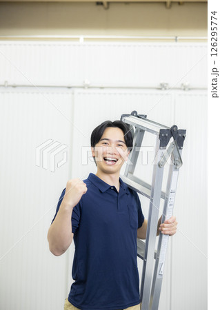 脚立を持ってガッツポーズをする若い男性 126295774