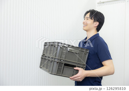 コンテナボックスを運ぶ男性 126295810