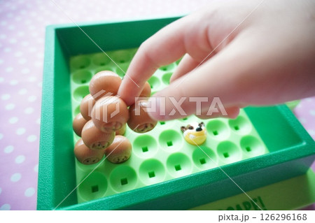 小学生の子供がボードゲーム遊びを楽しんでいる様子。駒を動かしている手元。 126296168