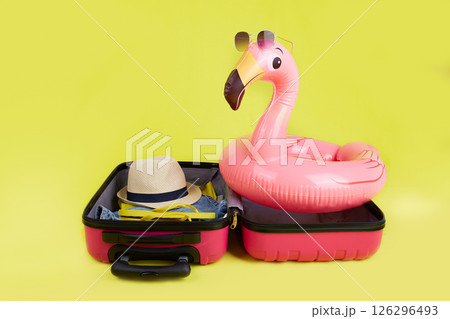 A suitcase with clothes and a pink inflatable pink flamingo for swimming  126296493