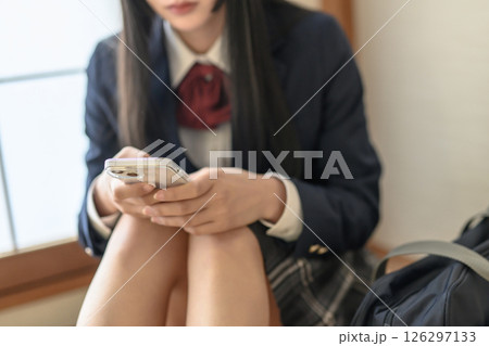 和室内でスマホを見る女子高生　連絡　進路相談　SNS　ポジティブ　明るめナチュラルカラー　 126297133