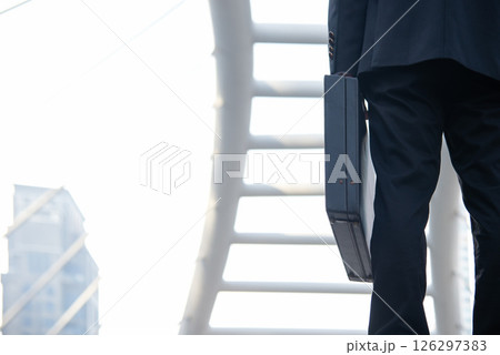 Close up hand holding business bag on the street. Unrecognizable businessman walking 126297383