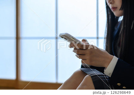 和室内でスマホを見る女子高生　いじめ　不登校　SNSトラブル　朝カラー 126298649