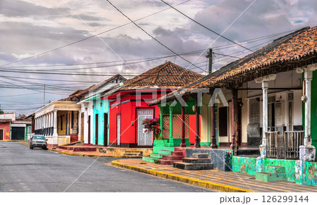 Row of vibrant colonial-style houses with ornate balconies, arched windows, and lush greenery lines a narrow cobblestone street in Granada, Nicaragua. The pastel colors and architectural details Row of vibrant colonial-style houses with ornate balconies, arched windows, and lush greenery lines a narrow cobblestone street in Granada, Nicaragua. The pastel colors and architectural details 126299144