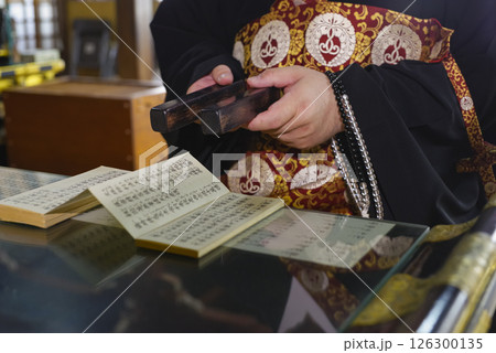 お寺の本堂で読経をするお坊さん 126300135