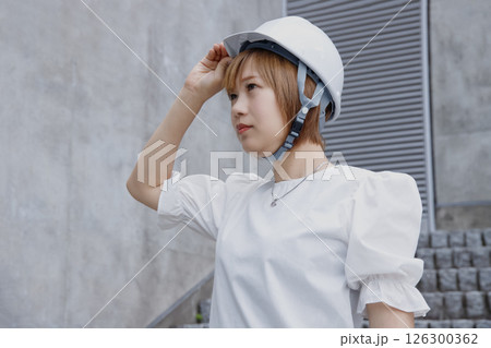 ヘルメットをかぶった横顔の女性とコンクリートの壁背景 ヘルメットをかぶった横顔の女性とコンクリートの壁背景 126300362