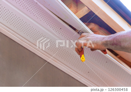 Contractor hand reaches up to install ceiling panel in home renovation during works day 126300458