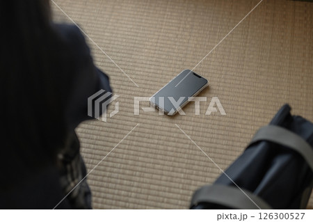 和室の畳に置かれたスマホを見る女子高生　いじめ　不登校　SNSトラブル　トリミングアップ 126300527