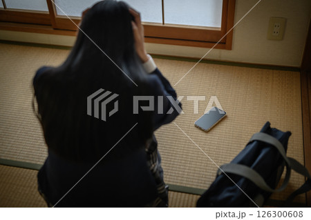 和室の畳に置かれたスマホを見る女子高生　いじめ　不登校　SNSトラブル　ナチュラルカラー 126300608