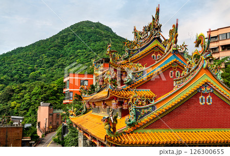 The ornate rooflines of Jiufen Xiahai City God Temple stand out against the lush green hills of New Taipei, Taiwan. This Taoist temple is richly decorated with dragons, deities, and intricate carvings The ornate rooflines of Jiufen Xiahai City God Temple stand out against the lush green hills of New Taipei, Taiwan. This Taoist temple is richly decorated with dragons, deities, and intricate carvings 126300655