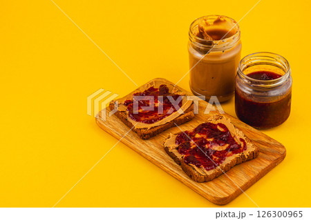 Peanut butter and jelly toast on wooden board with jars 126300965