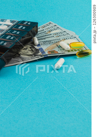 Money and medications arranged on a blue background Money and medications arranged on a blue background 126300989