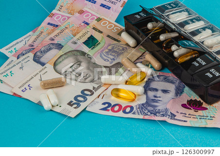 Currency and medication displayed on a blue background 126300997