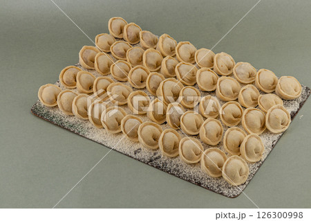 Homemade dumplings lined up on a floured surface ready to cook 126300998