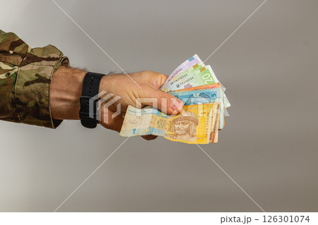 Hand holding assorted banknotes against a plain background 126301074