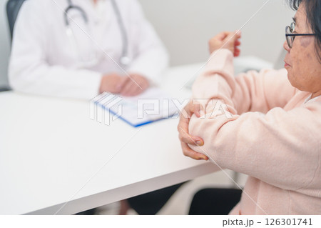 Elderly Woman having elbow ache and consulting doctor in hospital. muscle pain due to lateral epicondylitis or tennis elbow. injury, Health and medical consultation concept Elderly Woman having elbow ache and consulting doctor in hospital. muscle pain due to lateral epicondylitis or tennis elbow. injury, Health and medical consultation concept 126301741