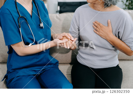 Young Caregiver doctor examine older patient use blood pressure gauge. woman therapist nurse at nursing home taking care of senior elderly woman sit on sofa. 126302350