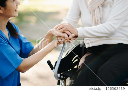 Elderly asian senior woman on wheelchair with Asian careful caregiver and encourage patient, walking in garden. with care from a caregiver. and senior health insurance 126302489