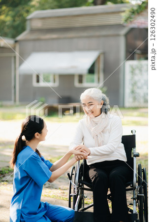 Elderly asian senior woman on wheelchair with Asian careful caregiver and encourage patient, walking in garden. with care from a caregiver. and senior health insurance 126302490