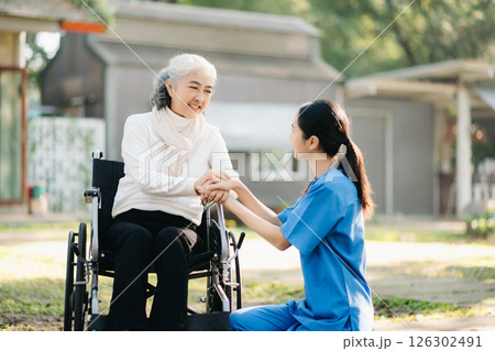 Elderly asian senior woman on wheelchair with Asian careful caregiver and encourage patient, walking in garden. with care from a caregiver. and senior health insurance 126302491