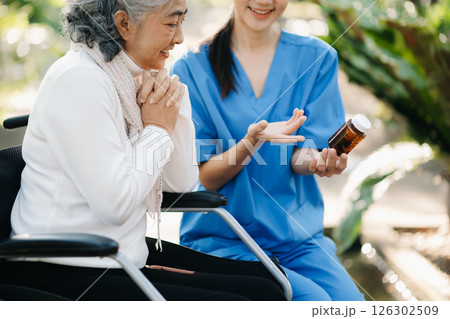 Elderly asian senior woman on wheelchair with Asian careful caregiver and encourage patient, walking in garden. with care from a caregiver. and senior health insurance Elderly asian senior woman on wheelchair with Asian careful caregiver and encourage patient, walking in garden. with care from a caregiver. and senior health insurance 126302509