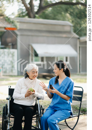 Elderly asian senior woman on wheelchair with Asian careful caregiver and encourage patient, walking in garden. with care from a caregiver. and senior health insurance Elderly asian senior woman on wheelchair with Asian careful caregiver and encourage patient, walking in garden. with care from a caregiver. and senior health insurance 126302514