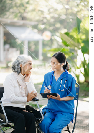 Elderly asian senior man on wheelchair with Asian careful caregiver. Nursing home hospital garden concept are walking in the garden. Elderly asian senior man on wheelchair with Asian careful caregiver. Nursing home hospital garden concept are walking in the garden. 126302546