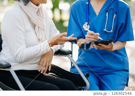 Elderly asian senior man on wheelchair with Asian careful caregiver. Nursing home hospital garden concept are walking in the garden. Elderly asian senior man on wheelchair with Asian careful caregiver. Nursing home hospital garden concept are walking in the garden. 126302548