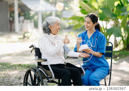 Elderly asian senior woman on wheelchair with Asian careful caregiver and encourage patient, walking in garden. with care from a caregiver 126302567