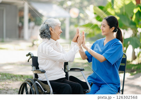 Elderly asian senior woman on wheelchair with Asian careful caregiver and encourage patient, walking in garden. with care from a caregiver 126302568