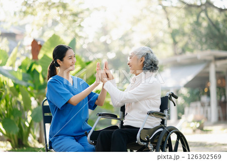 Elderly asian senior woman on wheelchair with Asian careful caregiver and encourage patient, walking in garden. with care from a caregiver 126302569
