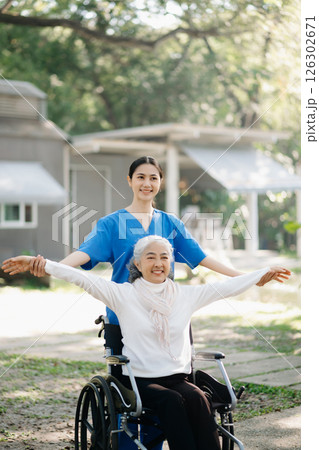Elderly asian senior woman on wheelchair with Asian careful caregiver and encourage patient, walking in garden. with care from a caregiver Elderly asian senior woman on wheelchair with Asian careful caregiver and encourage patient, walking in garden. with care from a caregiver 126302671