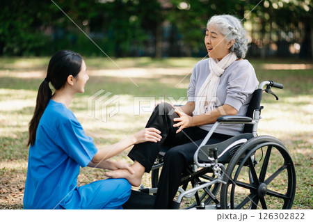 Asian physiotherapist helping elderly woman patient stretching arm during exercise correct with dumbbell in hand during training hand with patient Back problems in the garden. 126302822