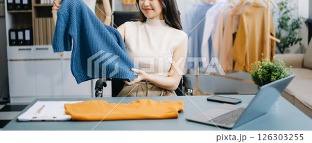 Asian young woman on desk in office of fashion designer and holds tablet, laptop and smartphone on desk Asian young woman on desk in office of fashion designer and holds tablet, laptop and smartphone on desk 126303255