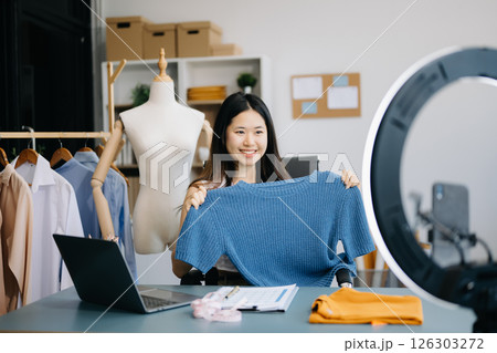 fashion designer. Attractive woman with smile while standing in workshop. Beautiful owner woman working and holds tablet, laptop and smartphone in studio. 126303272
