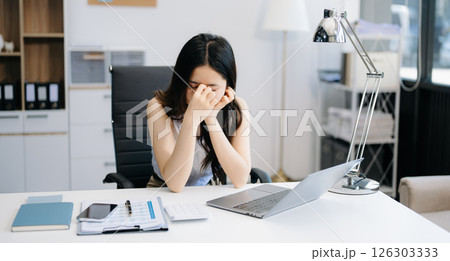 Overworked young Asian businesswoman office worker suffering from neck pain after had a long day at her office. office syndrome concept Overworked young Asian businesswoman office worker suffering from neck pain after had a long day at her office. office syndrome concept 126303333
